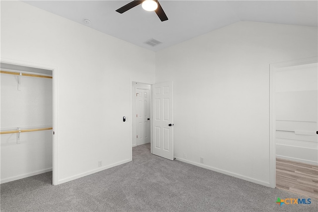 unfurnished bedroom featuring a closet, vaulted ceiling, light carpet, and ceiling fan