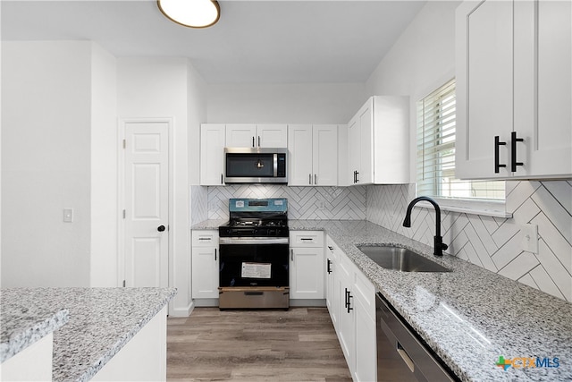 kitchen featuring light hardwood / wood-style floors, stainless steel appliances, sink, light stone countertops, and white cabinetry