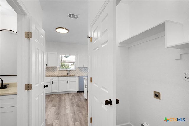 clothes washing area with hookup for an electric dryer, light wood-type flooring, and sink