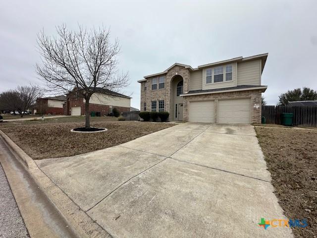 traditional-style home featuring a garage, driveway, and fence