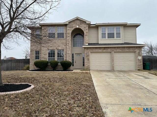 traditional-style home featuring concrete driveway, brick siding, an attached garage, and fence