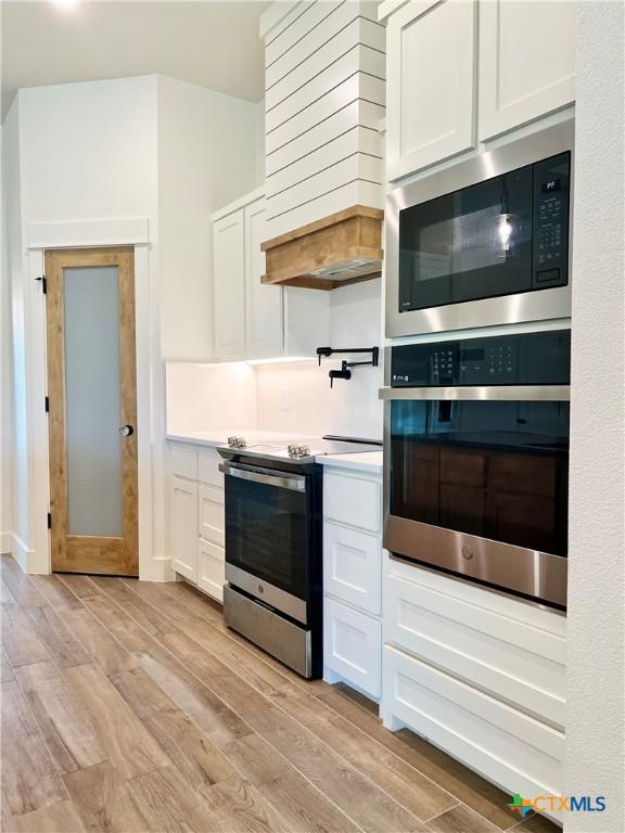 2819 Isaac Cir, Belton, TX 76513 - kitchen with stainless steel appliances, light wood-style floors, and white cabinetry