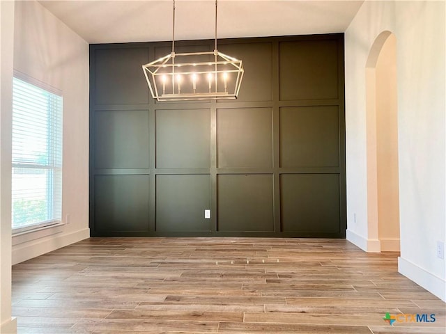 2819 Isaac Cir, Belton, TX 76513 - unfurnished dining area featuring a decorative wall, a chandelier, light wood-type flooring, arched walkways, and baseboards
