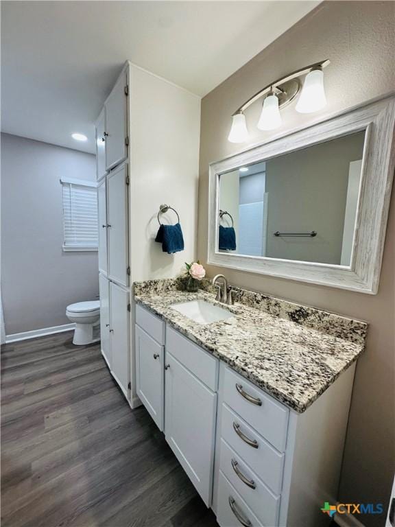 bathroom with hardwood / wood-style flooring, toilet, and vanity