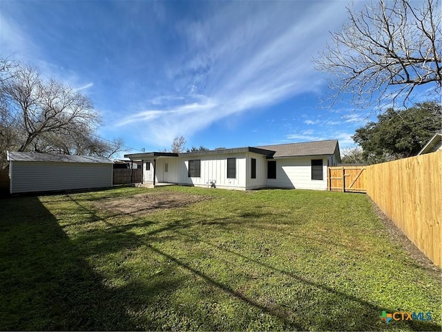 back of house with a storage shed and a yard