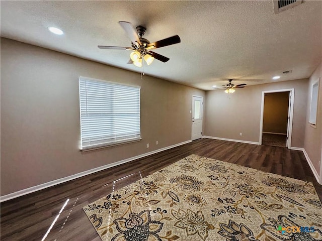 empty room featuring ceiling fan, dark wood-type flooring, and a textured ceiling