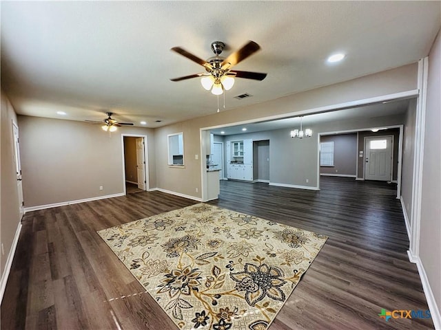 unfurnished living room featuring ceiling fan with notable chandelier and dark wood-type flooring