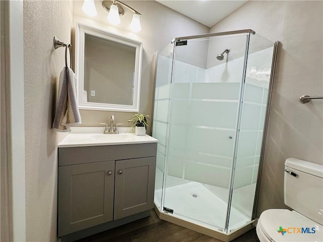 bathroom featuring hardwood / wood-style floors, toilet, vanity, and an enclosed shower