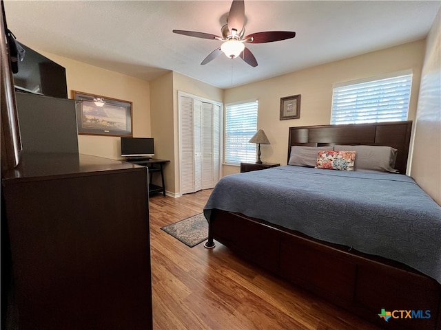 bedroom with ceiling fan, a closet, hardwood / wood-style floors, and multiple windows