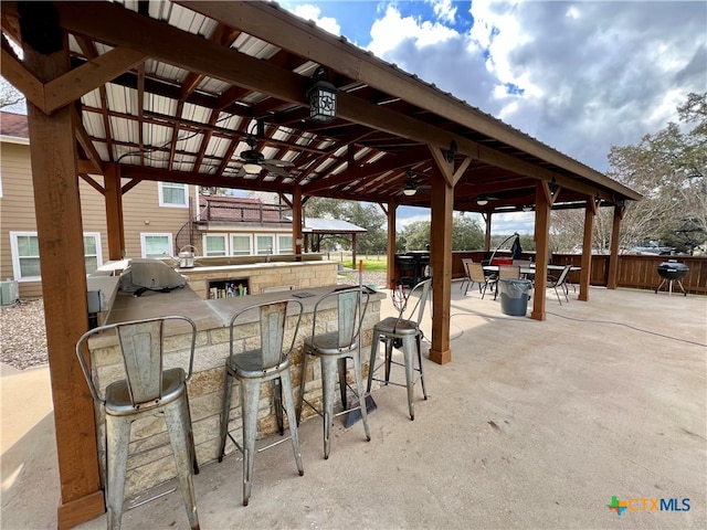 view of patio / terrace featuring ceiling fan, a grill, a gazebo, exterior bar, and cooling unit