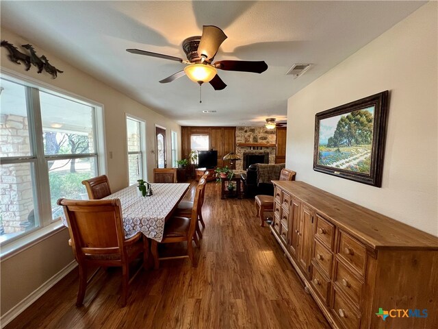 dining space with ceiling fan, dark wood-type flooring, and a fireplace