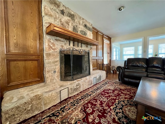 living room with wood-type flooring and a stone fireplace