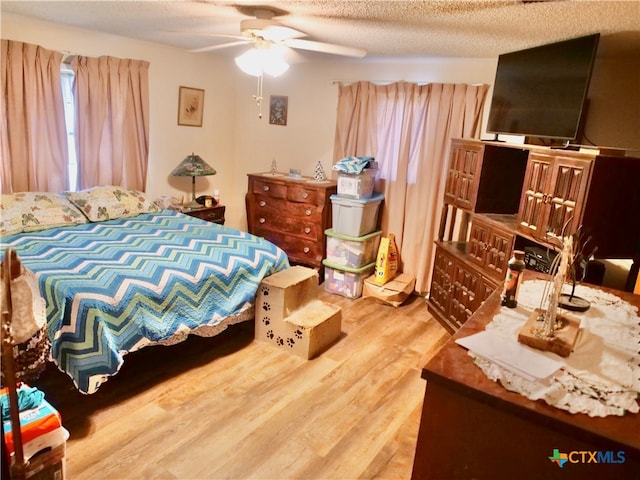 bedroom with a textured ceiling, hardwood / wood-style floors, and ceiling fan