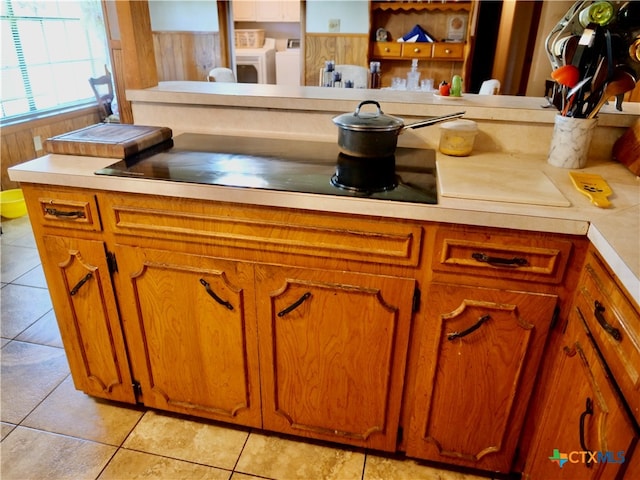 room details featuring wood walls, washing machine and dryer, and light tile patterned flooring