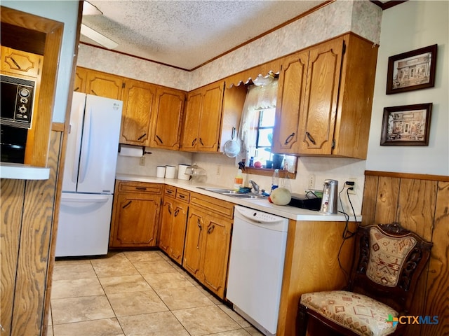 kitchen featuring sink, white appliances, a textured ceiling, and light tile patterned flooring