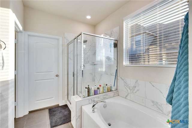 full bath with a stall shower, tile patterned flooring, and a bath