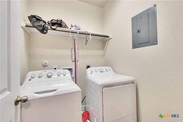 laundry area featuring a textured wall, laundry area, washing machine and dryer, and electric panel