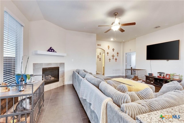 tiled living area with a tile fireplace, visible vents, ceiling fan, and baseboards