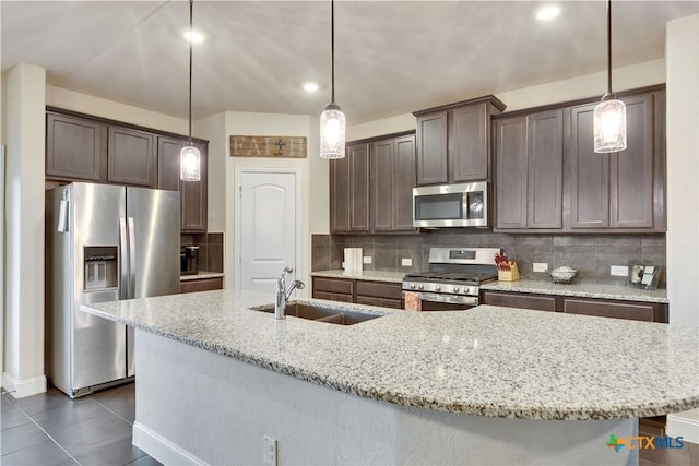 kitchen featuring dark brown cabinetry, appliances with stainless steel finishes, backsplash, and a sink