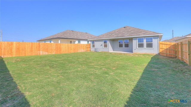 rear view of property featuring central AC and a yard