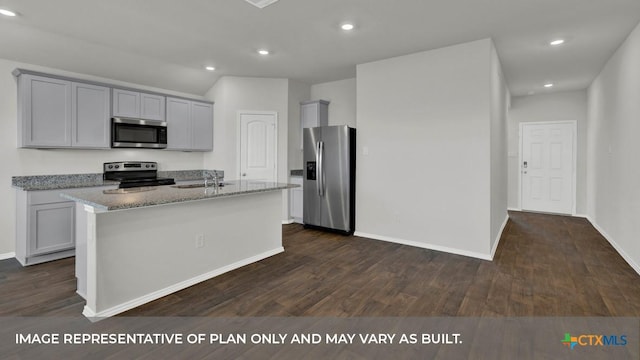 kitchen featuring dark hardwood / wood-style floors, light stone countertops, an island with sink, and appliances with stainless steel finishes