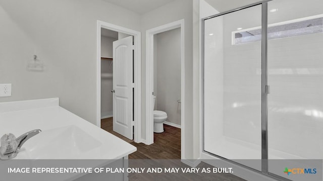 bathroom featuring wood-type flooring, vanity, toilet, and a shower with door