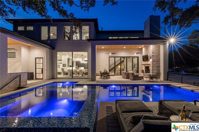 pool at twilight with outdoor lounge area, ceiling fan, a patio, and an in ground hot tub