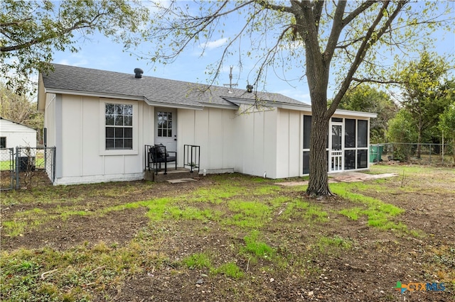 rear view of house with a lawn and a sunroom