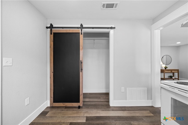 unfurnished bedroom featuring a barn door and dark hardwood / wood-style floors