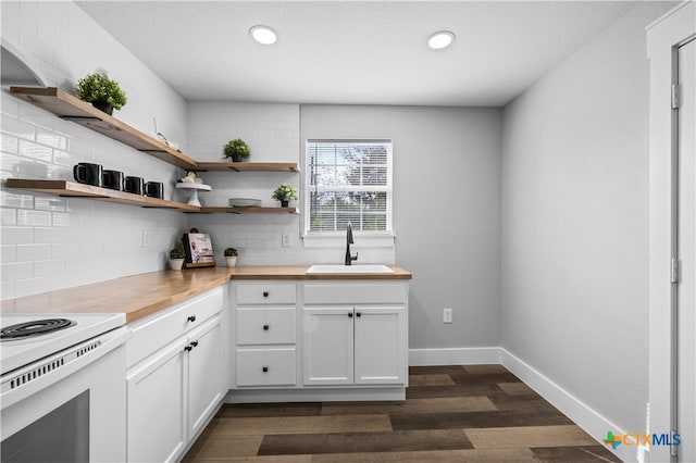 kitchen featuring butcher block countertops, sink, tasteful backsplash, dark hardwood / wood-style floors, and white cabinets