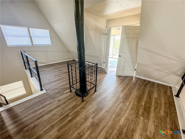 unfurnished living room with dark wood-type flooring, lofted ceiling, and a textured ceiling