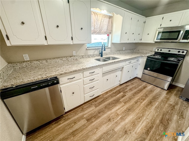 kitchen featuring white cabinets, light wood-type flooring, stainless steel appliances, and sink