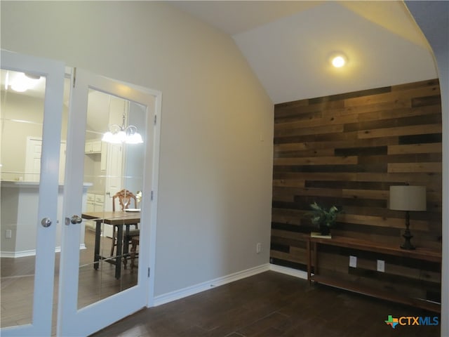 unfurnished living room featuring dark hardwood / wood-style flooring, an inviting chandelier, and vaulted ceiling