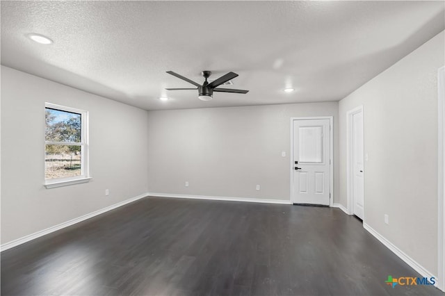 empty room with ceiling fan, dark hardwood / wood-style flooring, and a textured ceiling