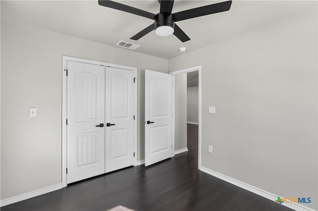 unfurnished bedroom featuring dark hardwood / wood-style flooring, ceiling fan, and a closet