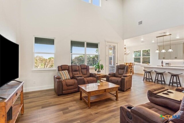 4851 Goliad Dr, Temple, TX 76502 - living room with baseboards, light wood finished floors, a chandelier, and a towering ceiling