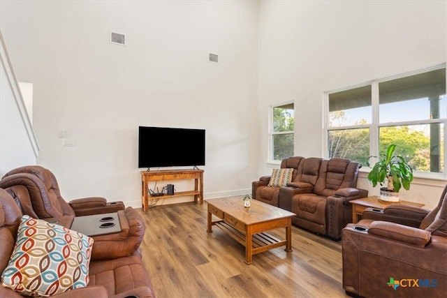 4851 Goliad Dr, Temple, TX 76502 - living area featuring visible vents, light wood-style flooring, a towering ceiling, and baseboards