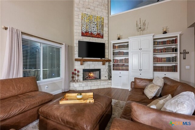 260 County Road 413, Spicewood, TX 78669 - living area with wood finished floors, a stone fireplace, baseboards, and a towering ceiling