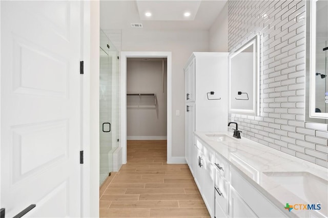 20029 Continental Dr, Lago Vista, TX 78645 - full bath featuring double vanity, a shower stall, baseboards, decorative backsplash, and wood finished floors