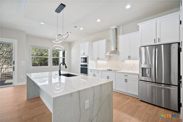 20029 Continental Dr, Lago Vista, TX 78645 - kitchen featuring appliances with stainless steel finishes, wall chimney range hood, a sink, light wood-style flooring, and recessed lighting