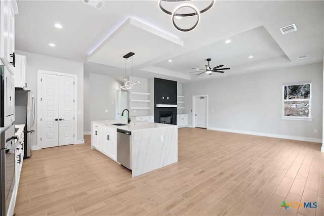 20029 Continental Dr, Lago Vista, TX 78645 - kitchen with a tray ceiling, appliances with stainless steel finishes, ceiling fan, a sink, and a multi sided fireplace