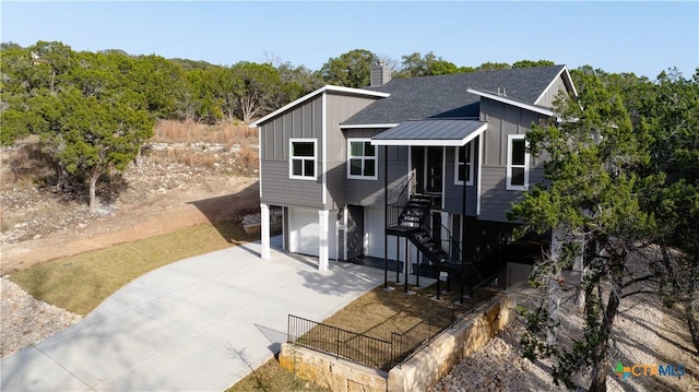 20029 Continental Dr, Lago Vista, TX 78645 - view of front facade with board and batten siding, an attached garage, driveway, stairs, and a chimney