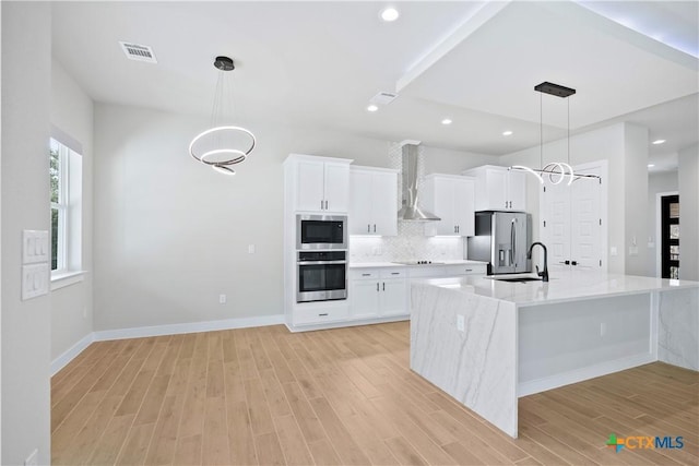 20029 Continental Dr, Lago Vista, TX 78645 - kitchen featuring stainless steel appliances, wall chimney range hood, a sink, light wood finished floors, and white cabinets