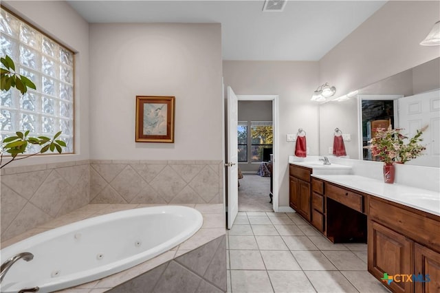 bathroom featuring tile patterned flooring, vanity, and tiled tub