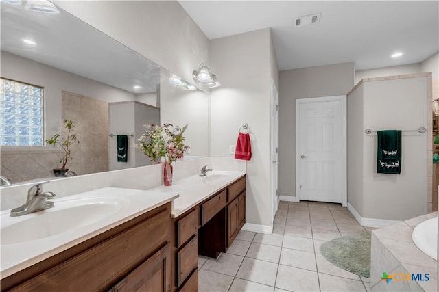 bathroom featuring tile patterned flooring, vanity, and tiled bath