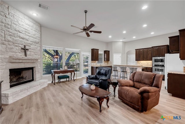 living room featuring ceiling fan, a fireplace, and light hardwood / wood-style floors