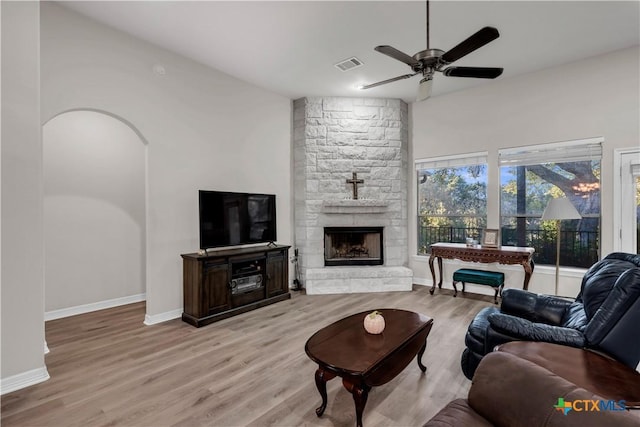 living room featuring a fireplace, light wood-type flooring, and ceiling fan