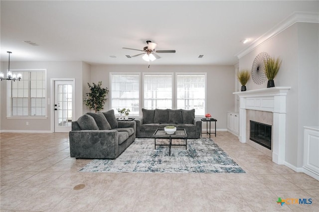 living area with ceiling fan with notable chandelier, baseboards, light tile patterned floors, a tile fireplace, and visible vents