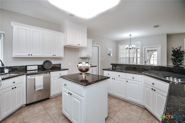 kitchen with white cabinets, a sink, light tile patterned floors, a notable chandelier, and stainless steel appliances
