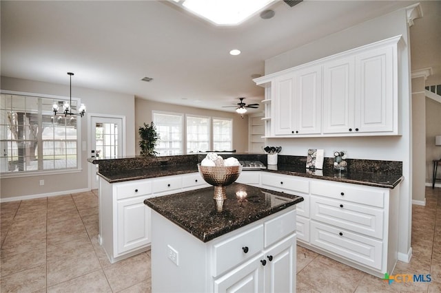 kitchen with baseboards, a peninsula, light tile patterned flooring, and a kitchen island